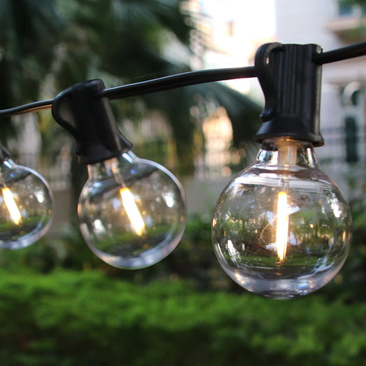 Close-up of glowing LED backyard lighting options featuring round bulbs hanging on a black wire outdoors