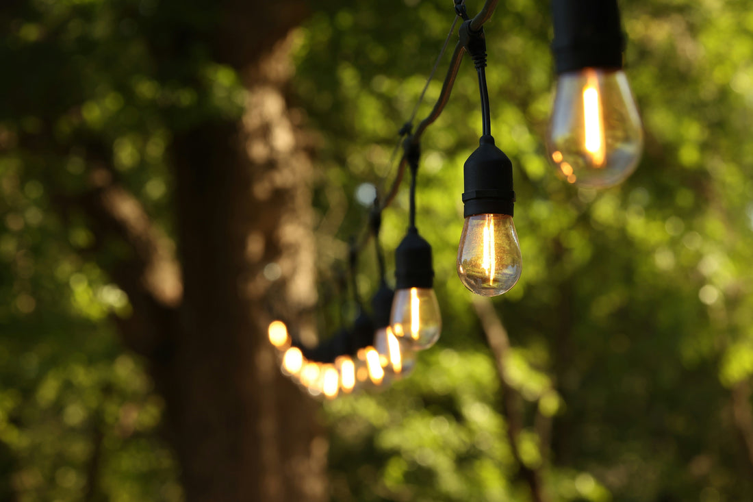 String lights hanging outdoors illuminating a patio area for DIY patio lighting guide