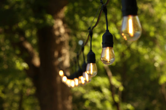 String lights hanging outdoors illuminating a patio area for DIY patio lighting guide