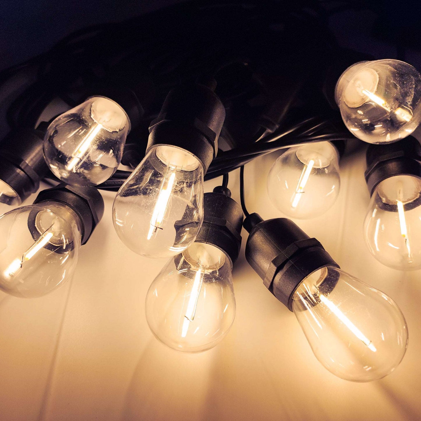String of warm white garden lights outdoor with clear bulbs and black sockets for outdoor decoration