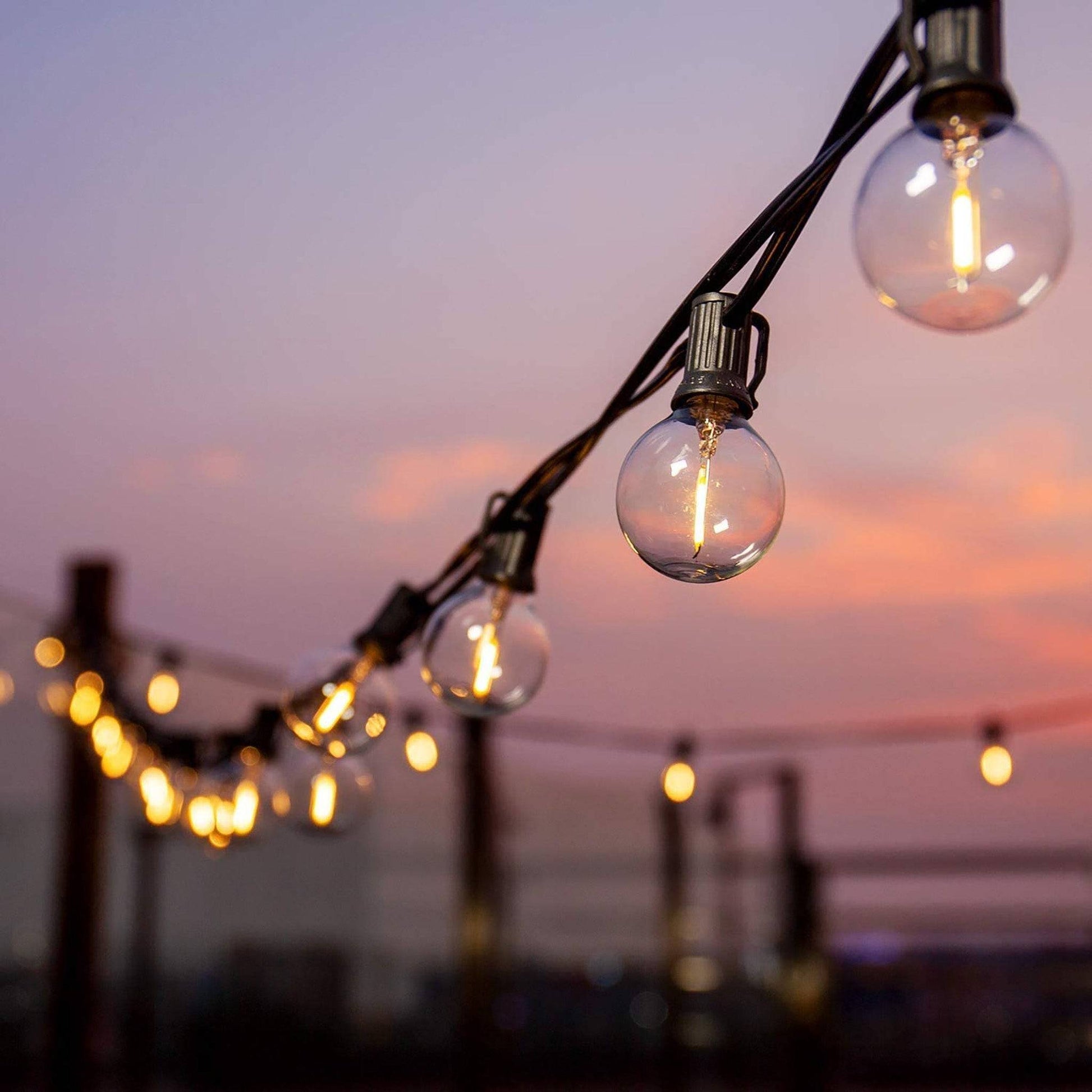 Garland solar outdoor lights hanging with glowing bulbs at sunset for outdoor decoration