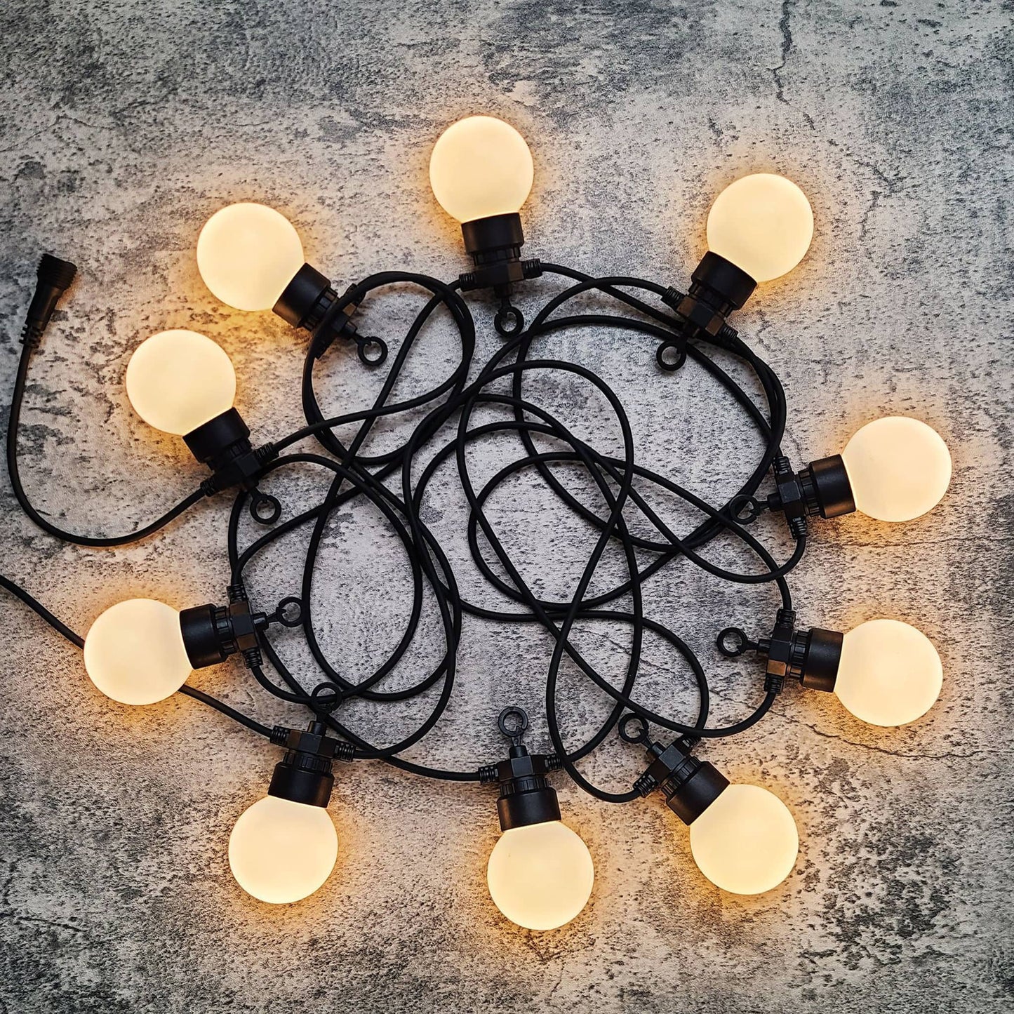 Outdoor string lights decoration with warm glowing bulbs on black wire for ambient lighting