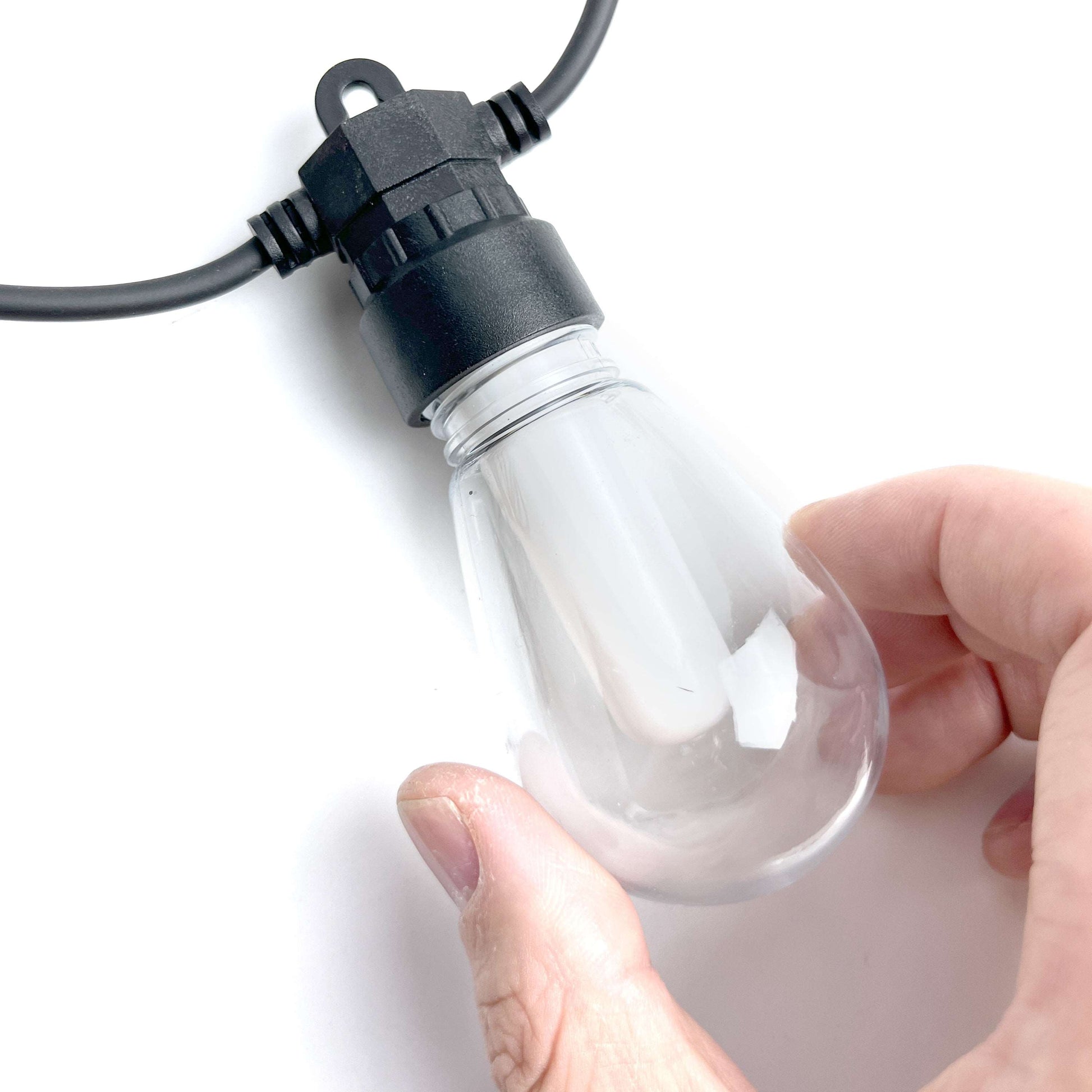 Hand holding clear bulb of outdoor fairy lights with black socket and cord by Ningbo Fuaisi