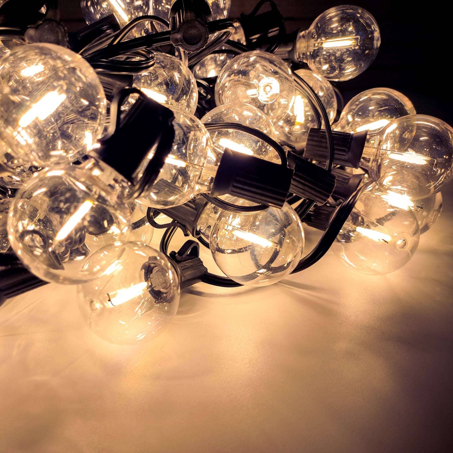 Warm glowing outdoor solar lights with round bulbs connected by black wiring for garden decoration