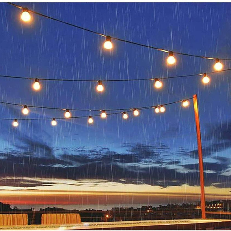 Outdoor solar lights string hanging in rainy evening sky providing warm glowing illumination
