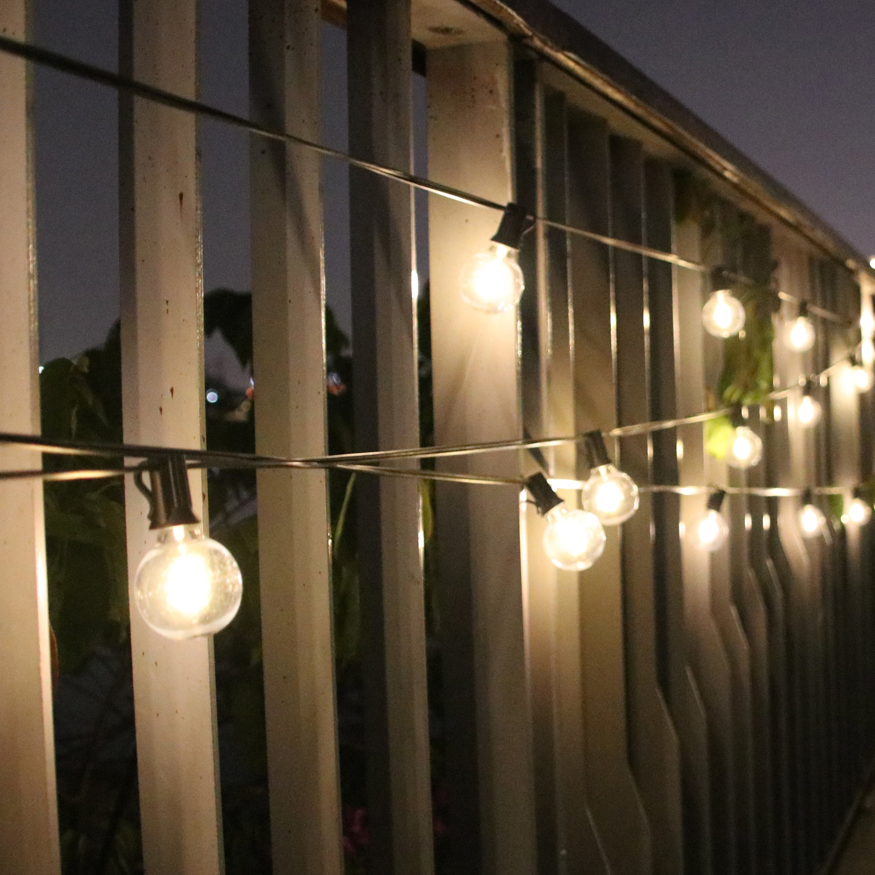 Waterproof LED string lights hanging on outdoor fence providing warm ambient lighting