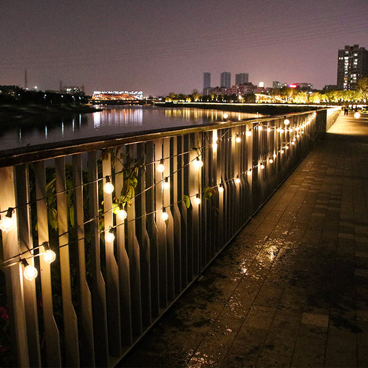 Best outdoor string lights hanging on a railing illuminating a riverside walkway at night