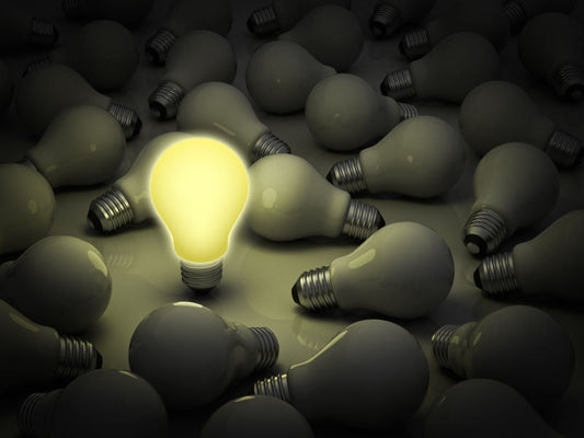 A glowing light bulb surrounded by unlit bulbs illustrating LED energy saving benefits