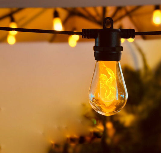 Close-up of a glowing string bulb among popular patio lights hanging outdoors at dusk