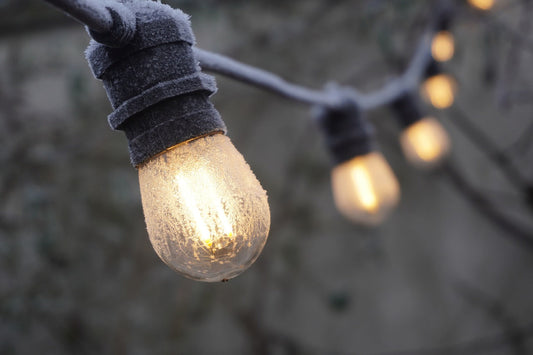 Close-up of energy-saving outdoor LED string lights glowing with frost on the bulbs in a winter setting