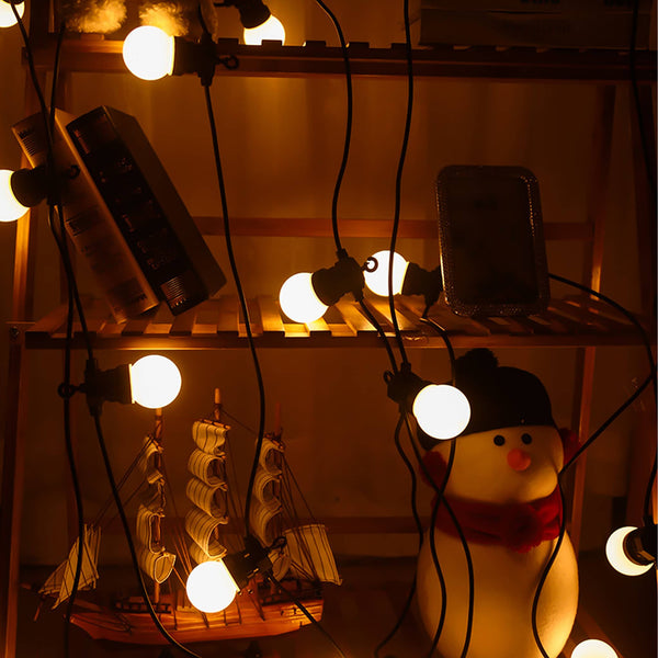Warm white outdoor lights decoration string illuminating shelves with books, model ship, and snowman figure