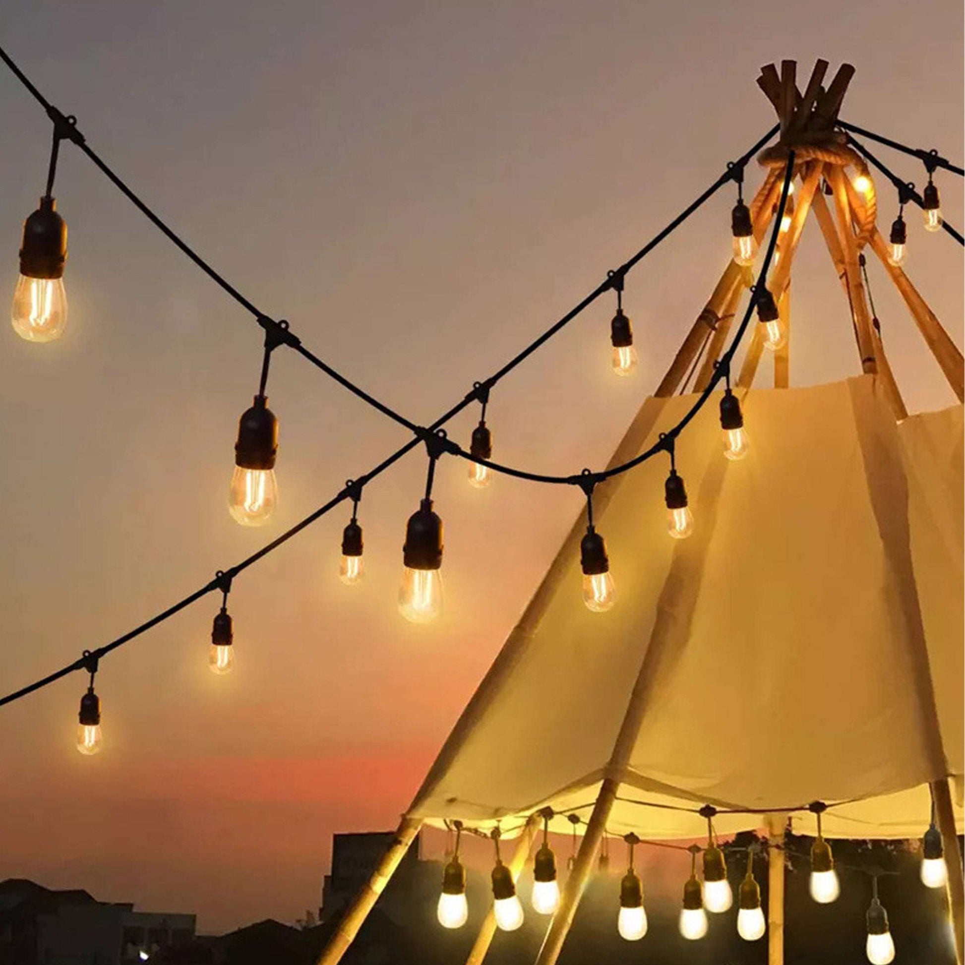 Outdoor commercial waterproof string lights hanging around a teepee structure at sunset
